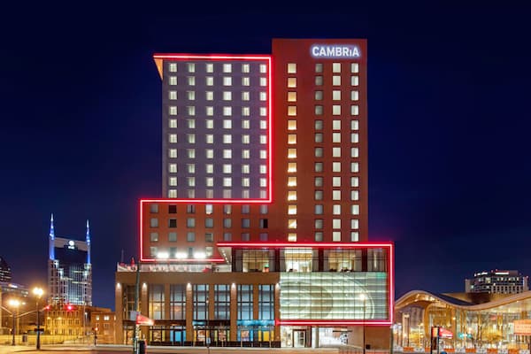 Exterior photo of a Cambria hotel with a neon red light outlining parts of the building