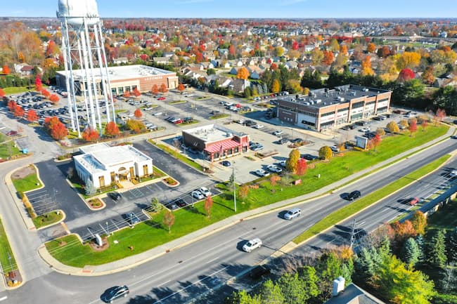 A drone photo of a city, with a water tower, street with cars, and several buildings
